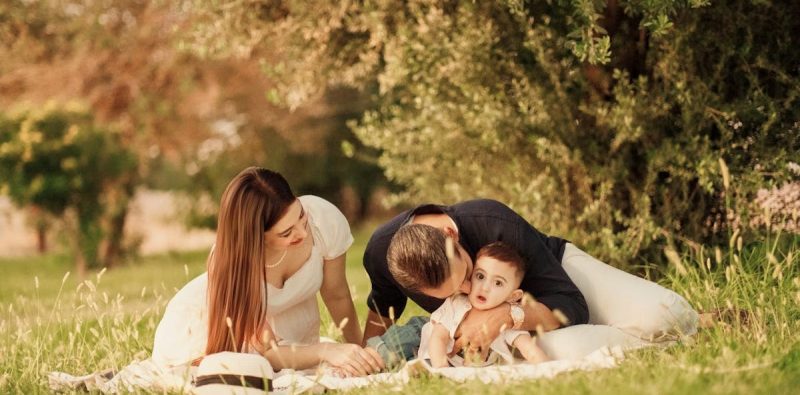 A happy family having a picnic in a lush green park setting during the day.